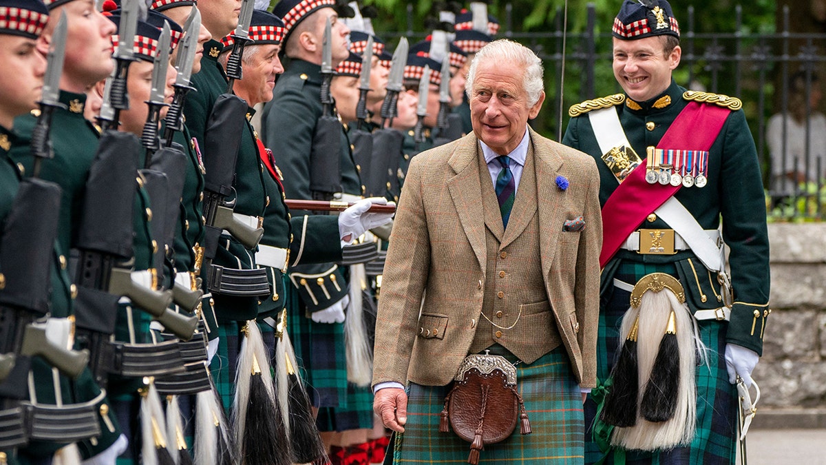 King Charles in traditional Scottish clothing being greeted by locals