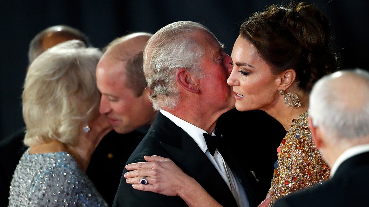 Kate Middleton in a gold gown being kissed on the cheek by King Charles