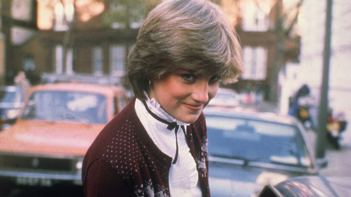 Lady Diana Spencer wearing a high collar white blouse and a purple sweater
