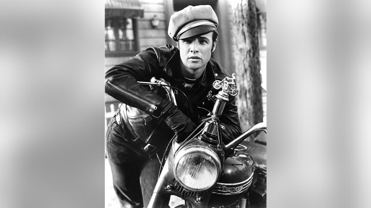 Marlon Brando wearing a leather jacket sitting on top of a motorcycle