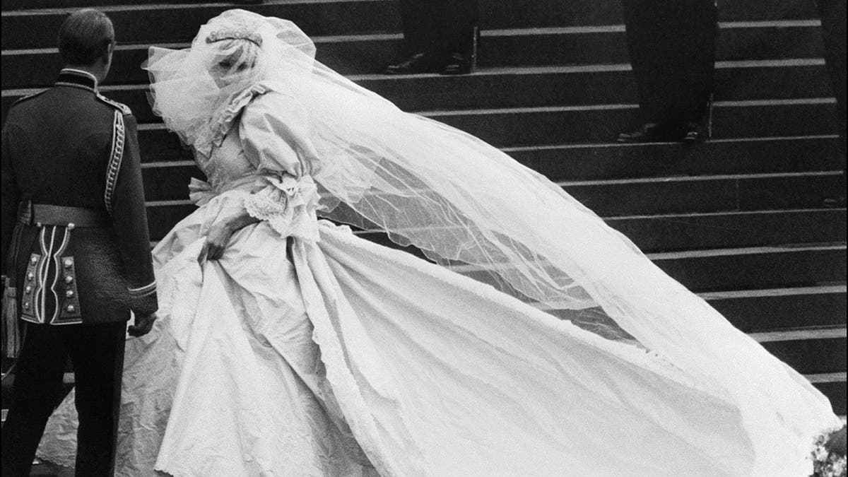 Princess Diana in her wedding dress walking alongside Prince Charles