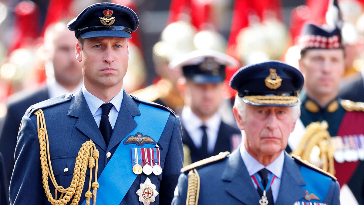 Prince William in a military suit walking behind his father King Charles