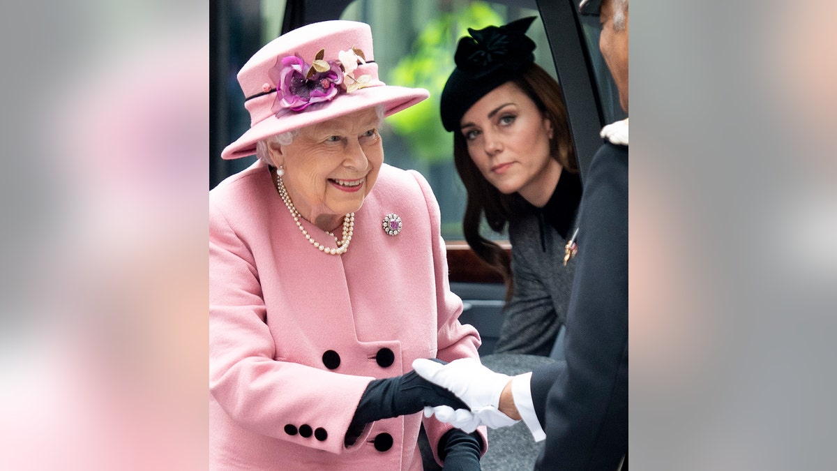Queen Elizabeth wearing a pink suit as Kate Middleton watches on