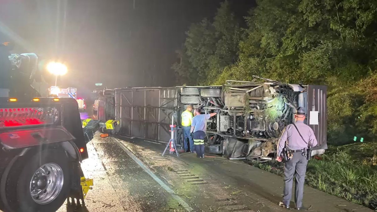 A bus on its side, people standing