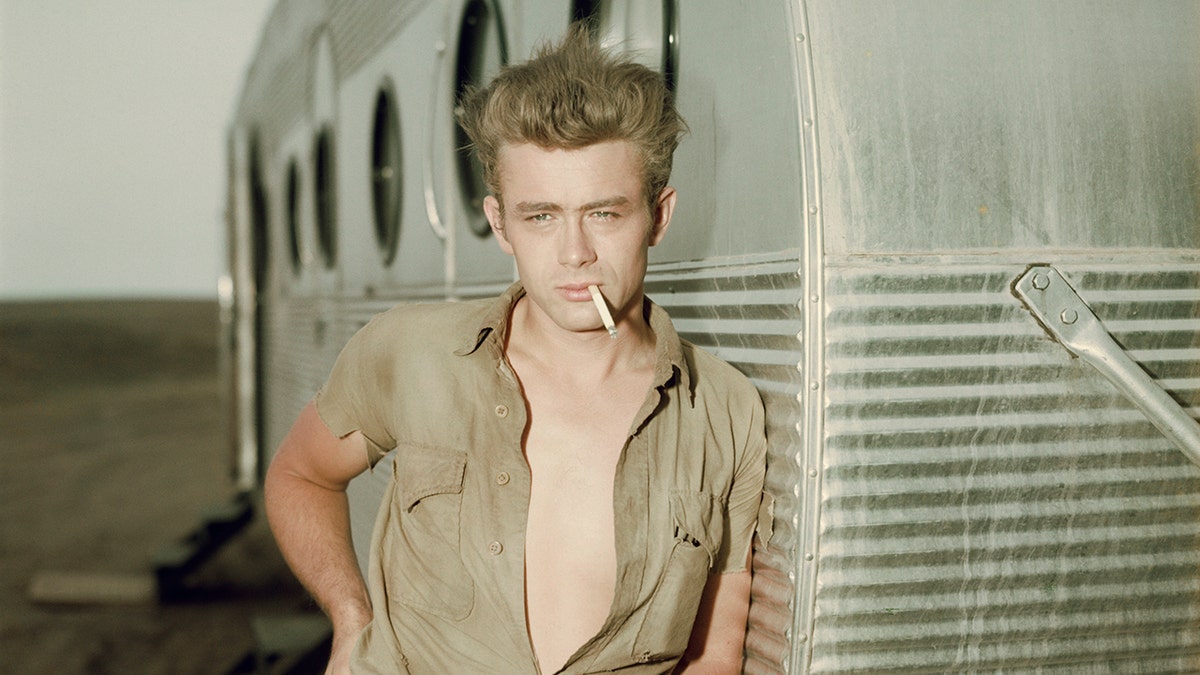 James Dean posing next to trailer with cigarette in his mouth