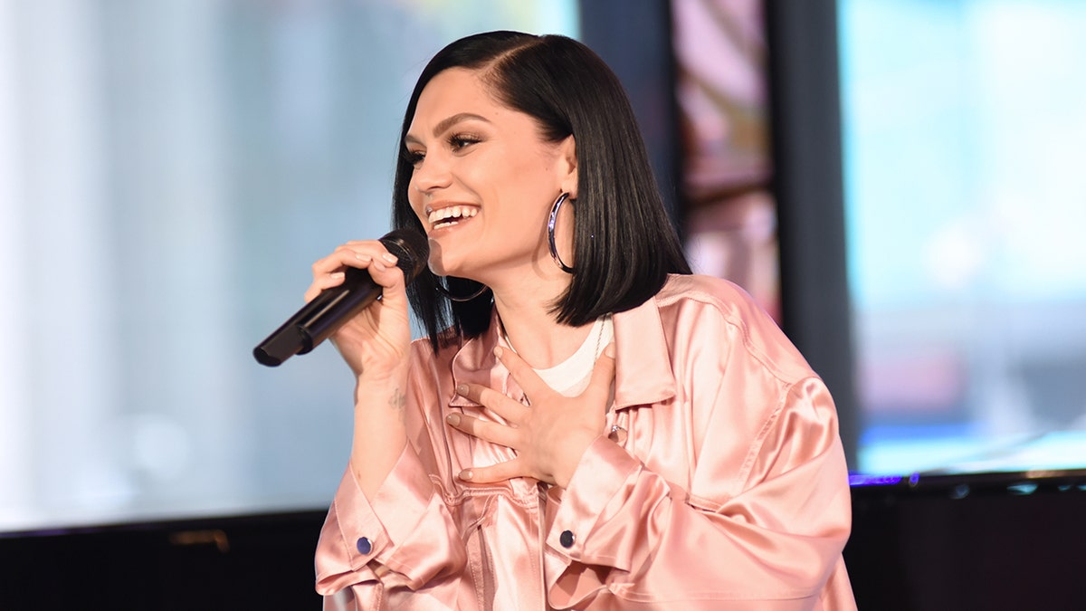Jessie J on TV holding microphone wearing a pink jacket
