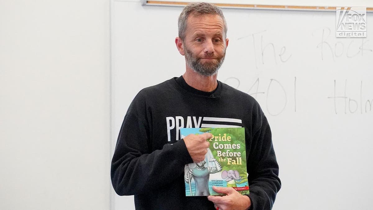 Kids in a big room sit on the floor as they are read to