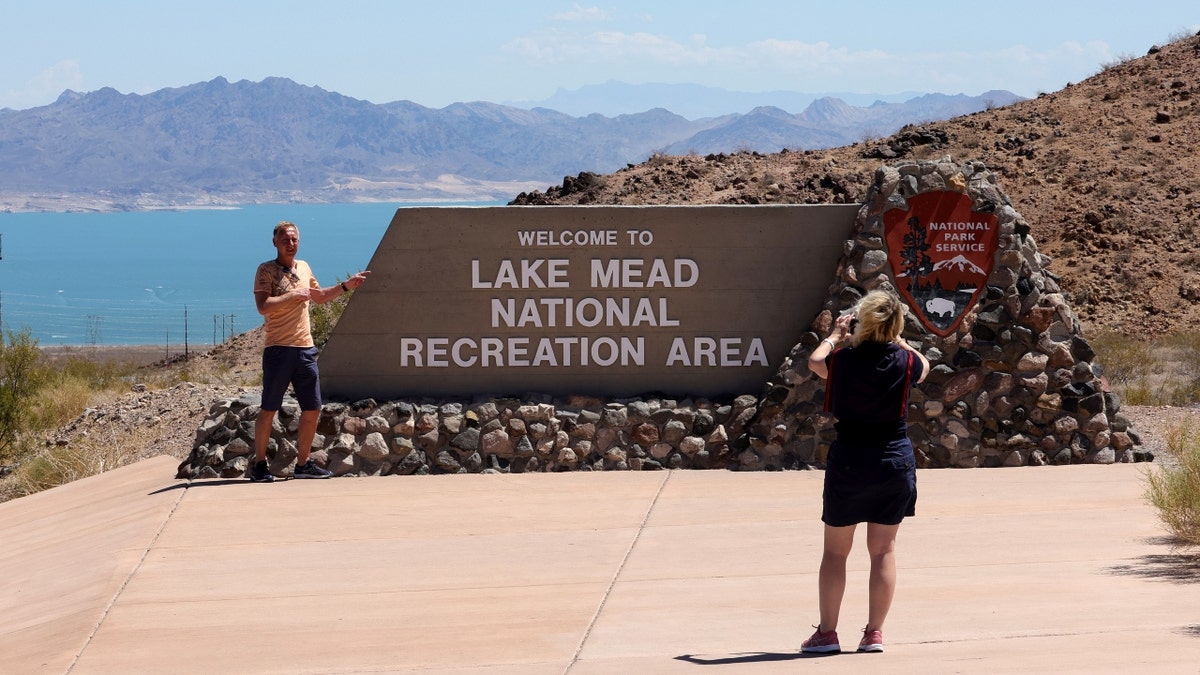 Tourists pose for photos at a sign for the Lake Mead National Recreation Area