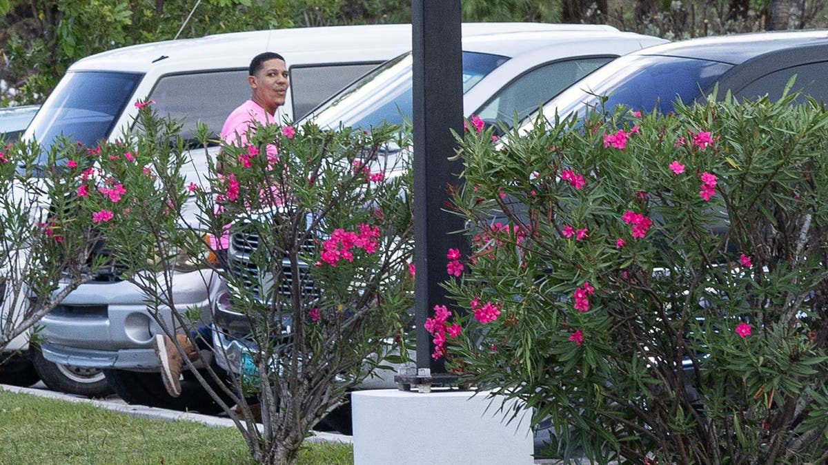 man in pink shirt walks to car