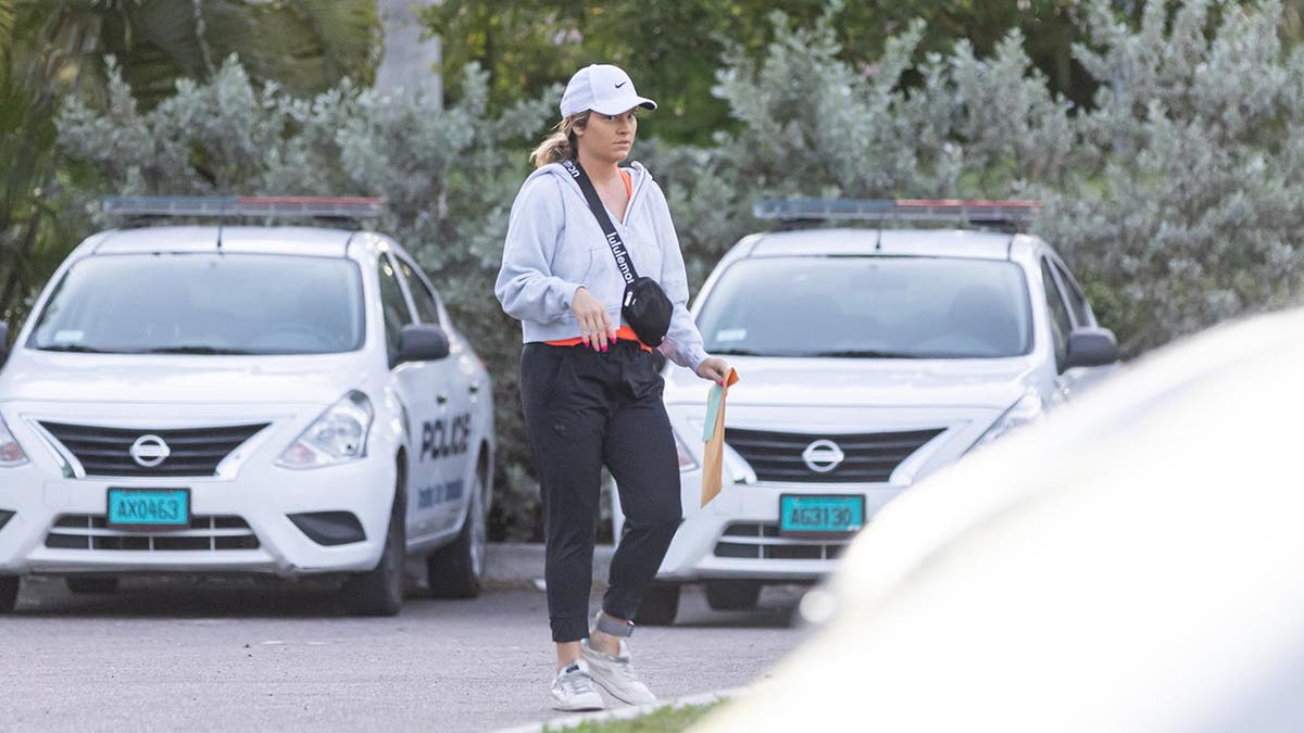 Lindsay Shiver in workout gear walks through a carpark holding a manila folder
