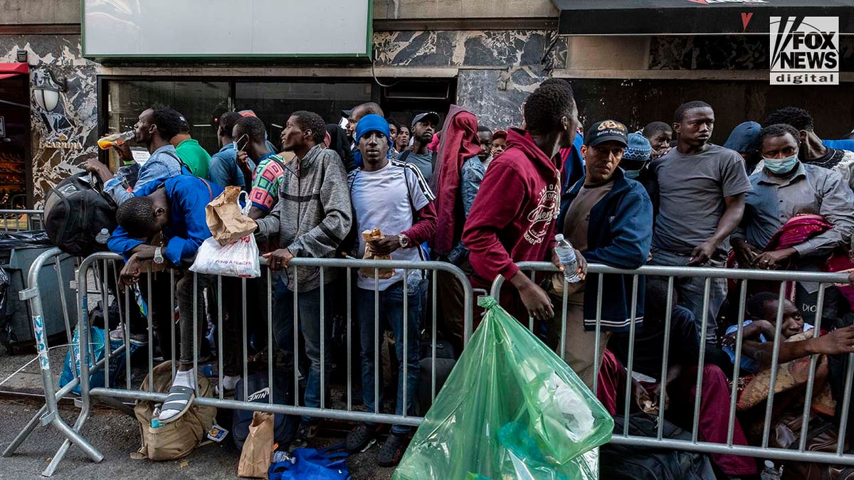 Migrants sit on the sidewalk in Manhattan