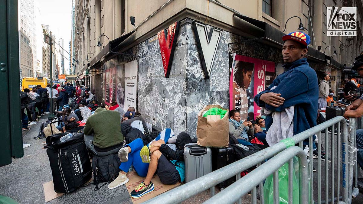 Migrants sit on the sidewalk in Manhattan