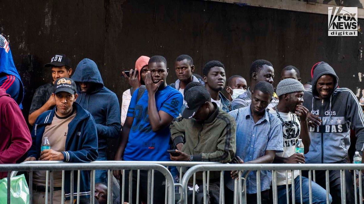 Migrants await registration outside of the Roosevelt Hotel