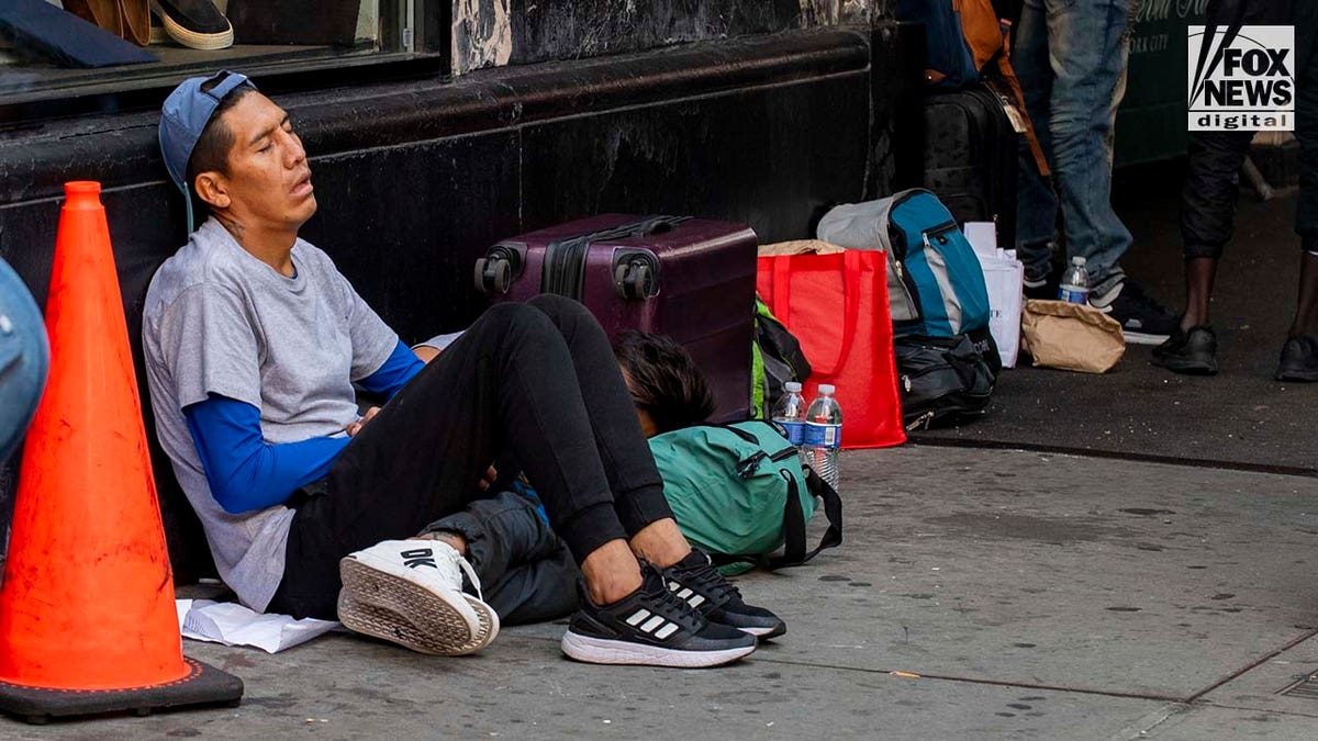 Migrant sitting on sidewalk outside hotel in NYC