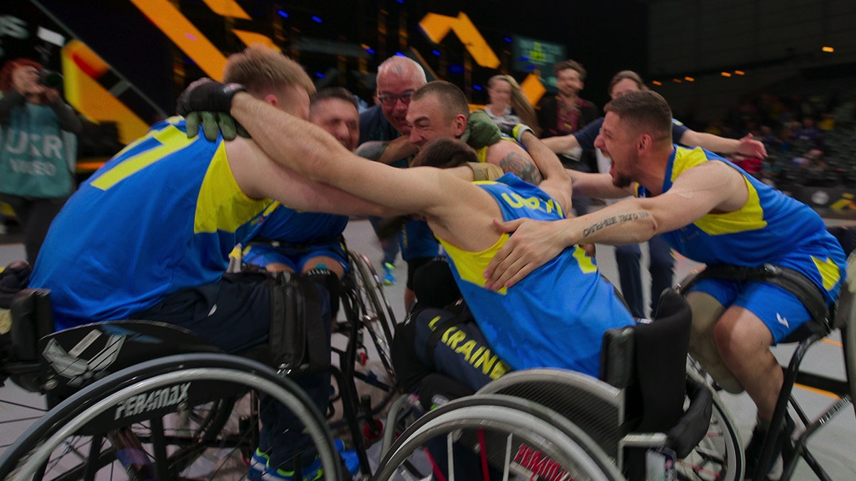 competitors in wheelchairs embracing each other