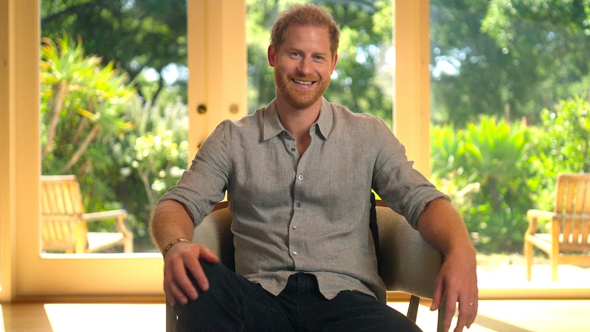 Prince Harry wearing a grey shirt and dark pants