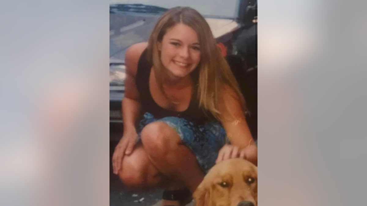 Christie Wilson kneeling down in a denim skirt and a brown tank top