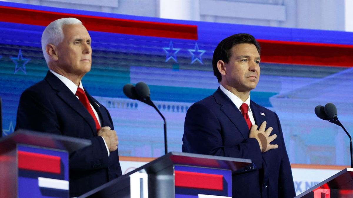 Pence and DeSantis during debate with right hand over heart