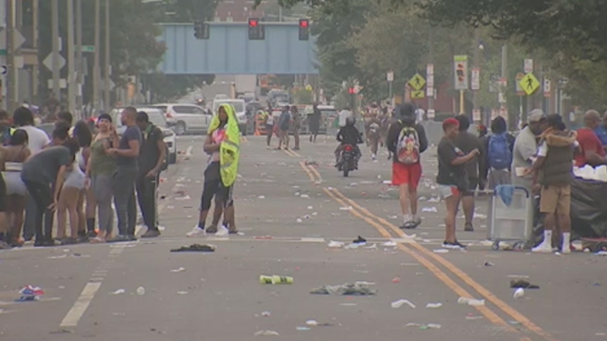 People gather on the streets in Boston where a shooting occurred at a festival, trash seen on the ground