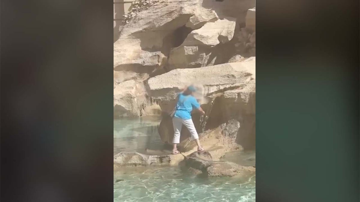Woman fills water bottle at Trevi Fountain