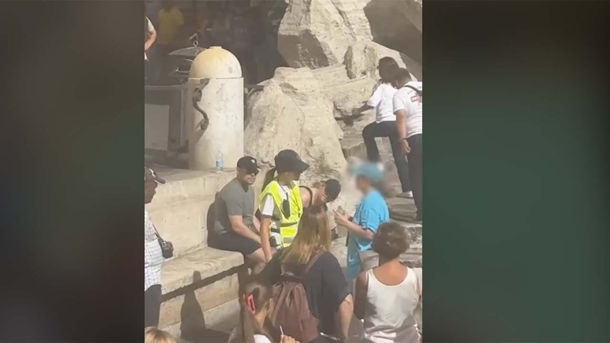 Security guard stops tourist at Trevi Fountain
