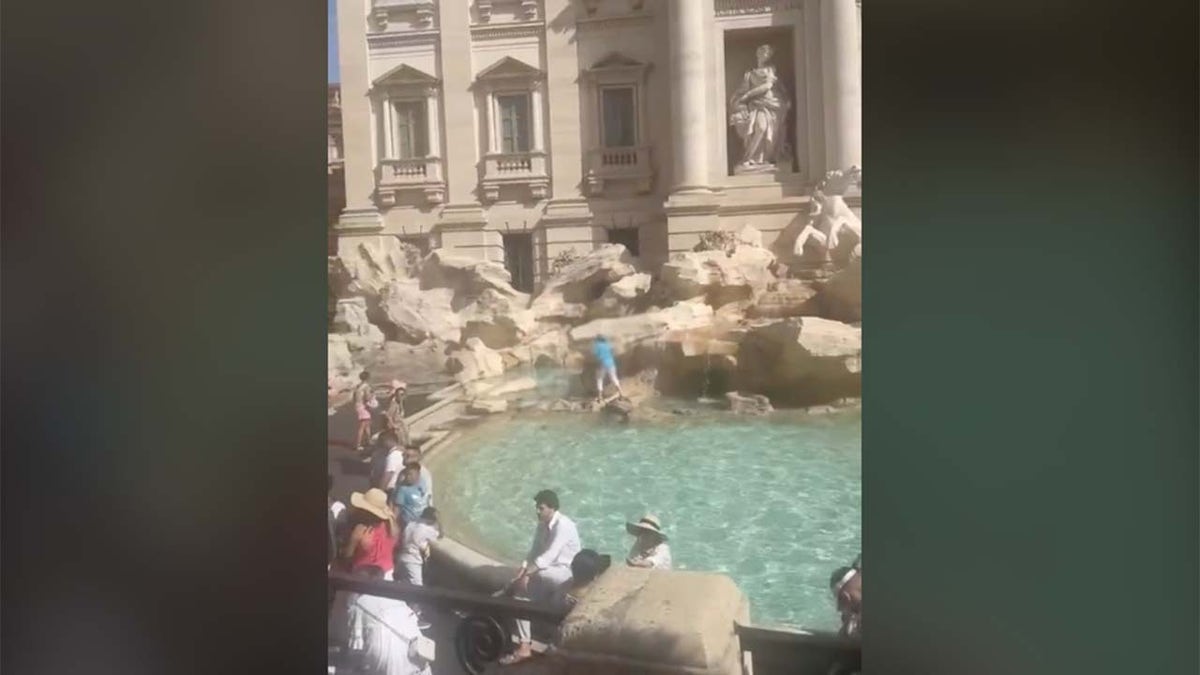 Tourist fills water bottle at Trevi Fountain