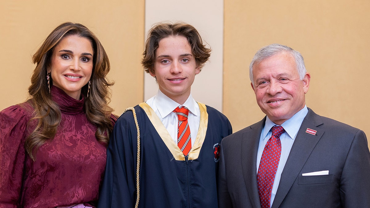 Prince Hashem in his graduation gown with his mother in a purple dress and his father in a navy suit