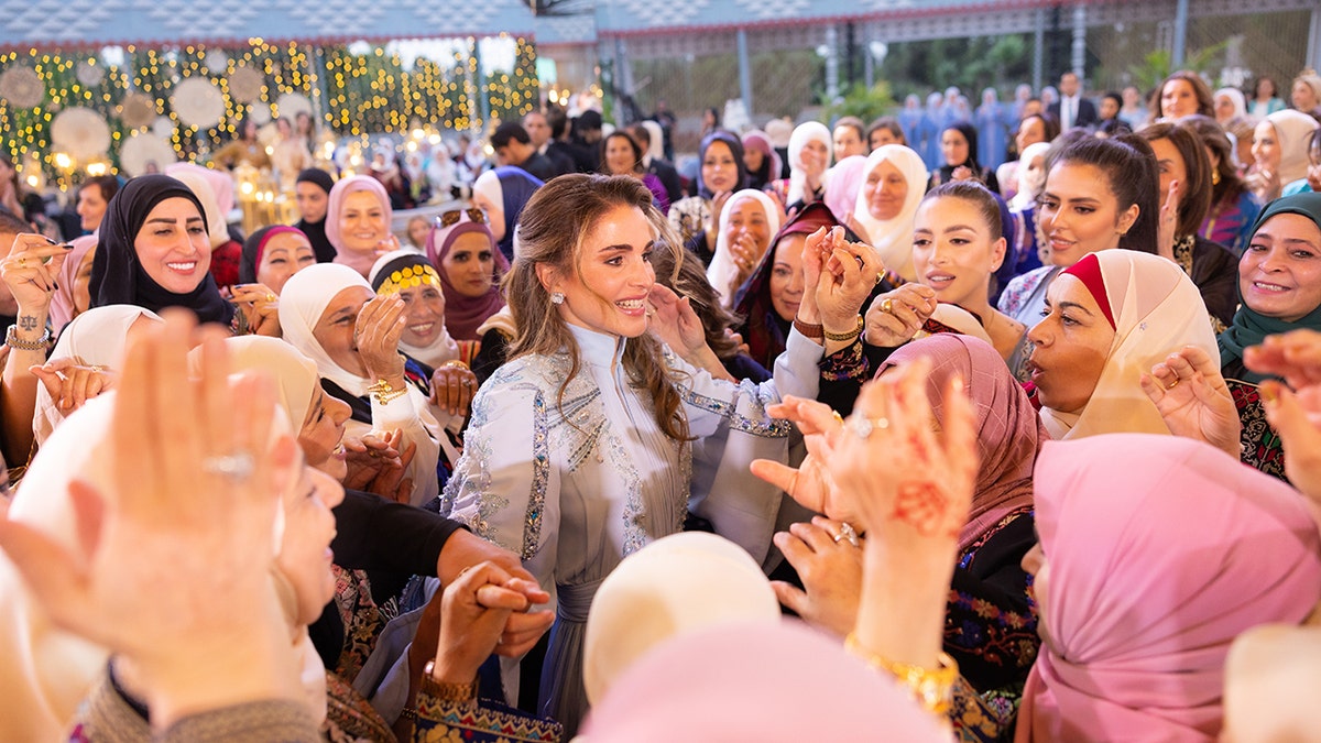 Queen Rania of Jordan being embraced by women outdoors