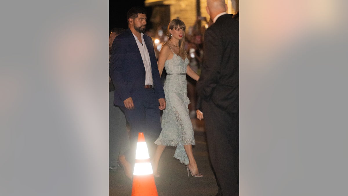 Taylor Swift walks with security in light blue lacy dress at rehearsal dinner