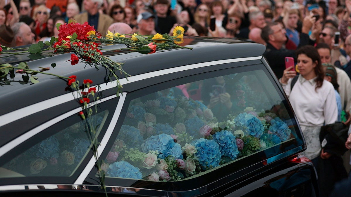 Sinead O'Connor's casket covered in flowers in the back of a hearse