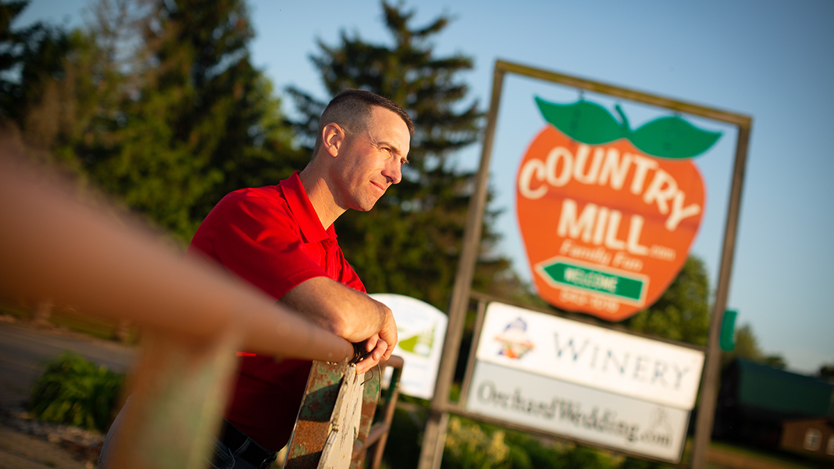 Steve Tennes poses by Country Mill Farms sign