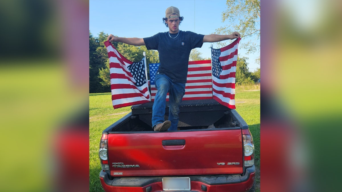 Christopher Hartless standing on red truck with American flags