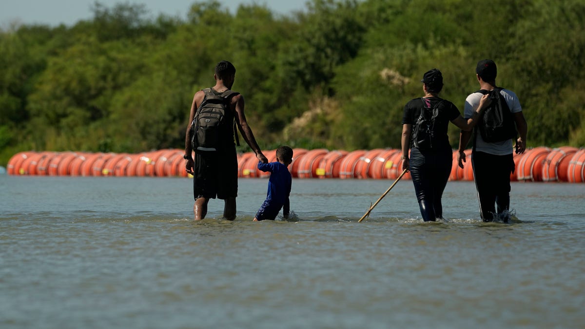 Migrants walk near Texas floating border barrier
