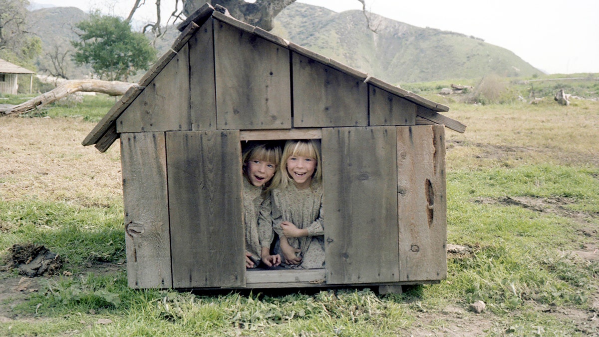 Wendi Lou Lee and her twin sister Brenda in costume inside a wooden dog house