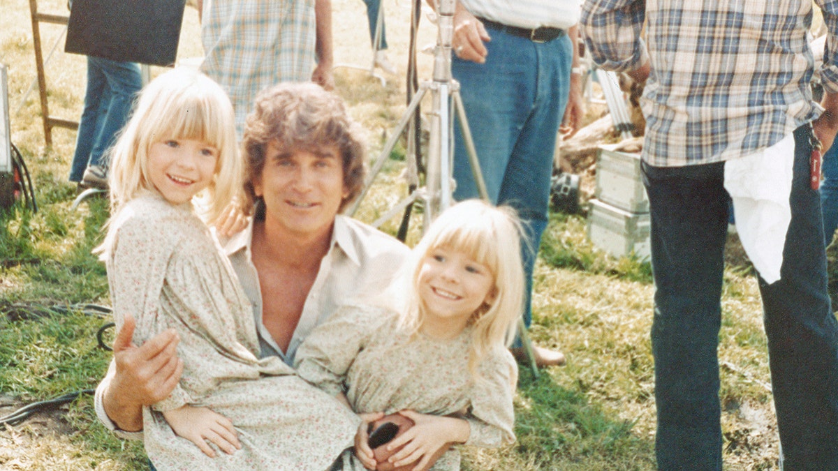 Wendi Lou Lee and her twin sister in costume smiling while being held by Michael Landon