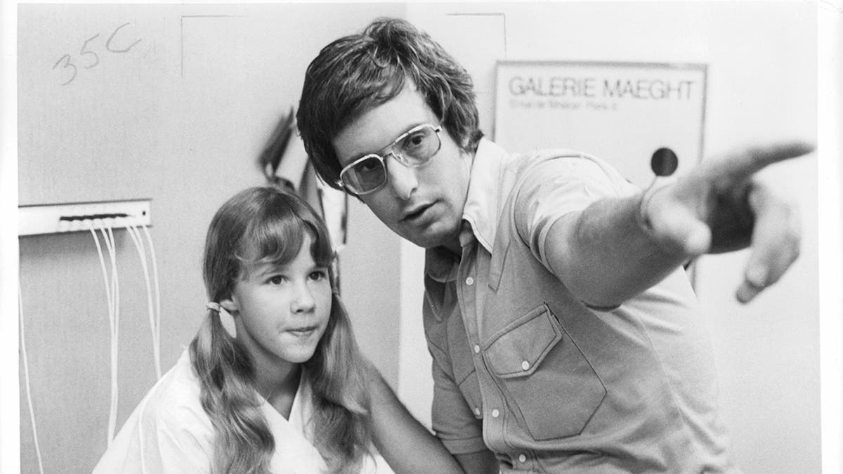 Black and white photo of young Linda Blair being directed by William Friedkin