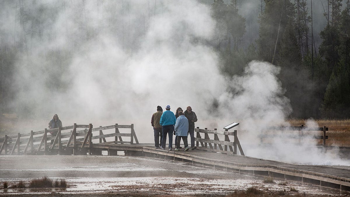 People walk on boardwalk at Yellowstone National Park