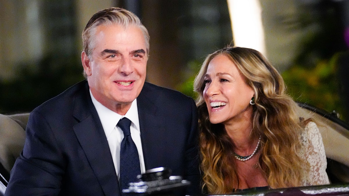 Chris Noth as 'Big' in a dark suit sits next to Sarah Jessica Parker as Carrie Bradshaw while filming 'And Just Like That' in New York City