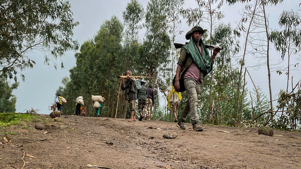 militia fighter walks as residents flee