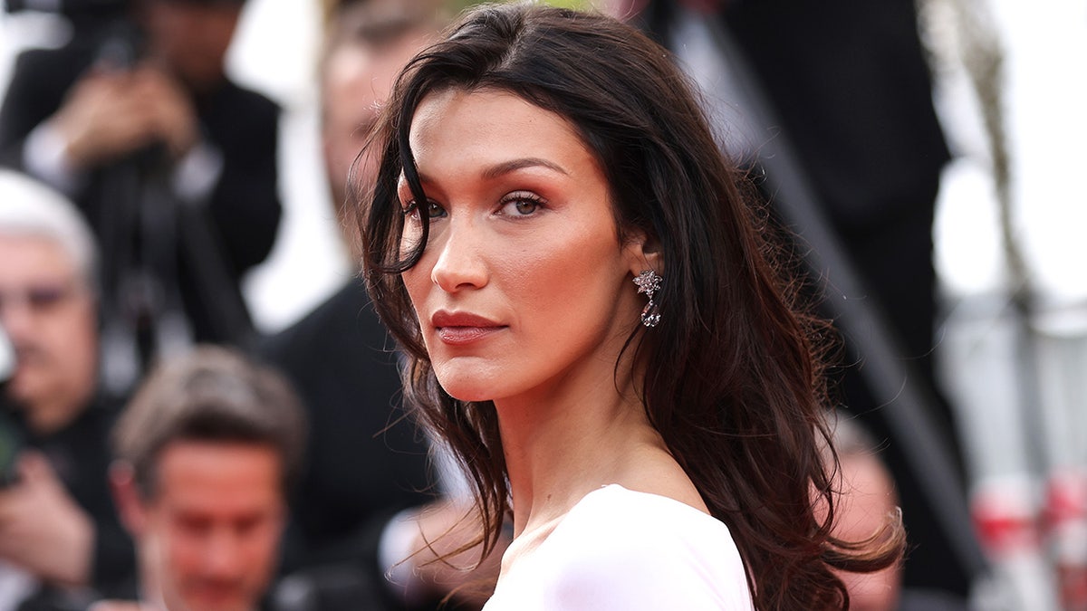 Bella Hadid in a white dress with a strand of hair in her right eye on the Cannes red carpet