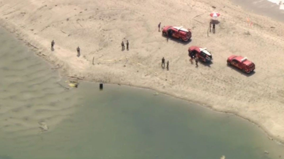 authorities at beach investigating barrel