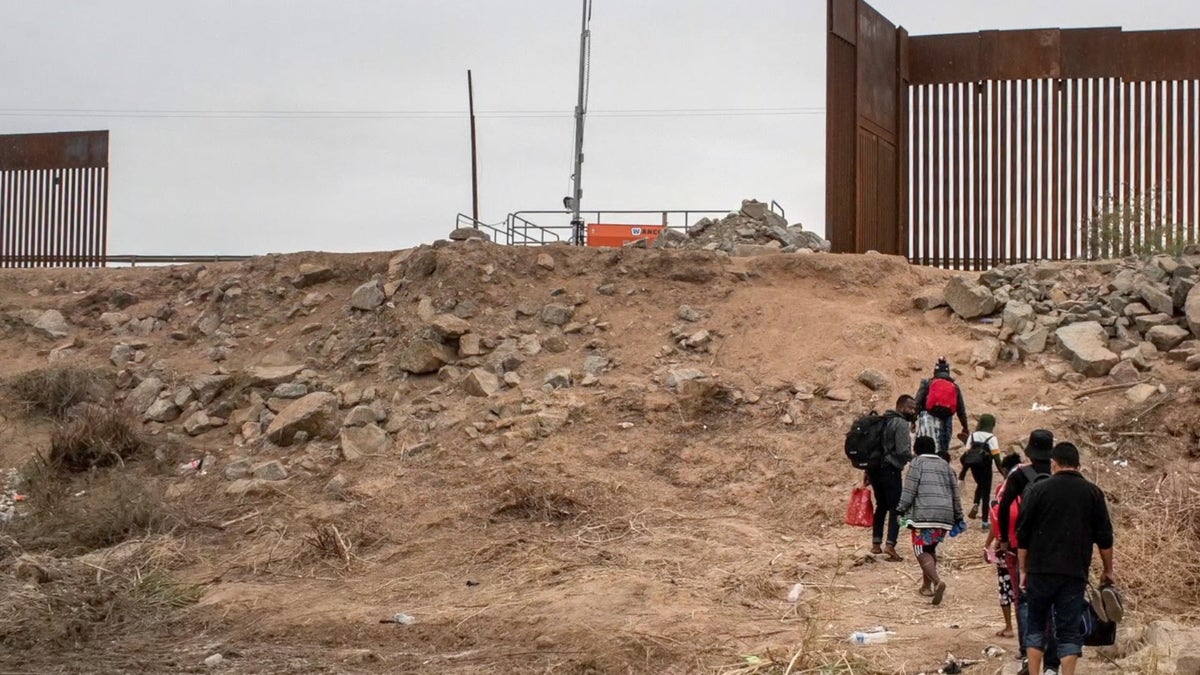 Migrants walking toward border wall gap