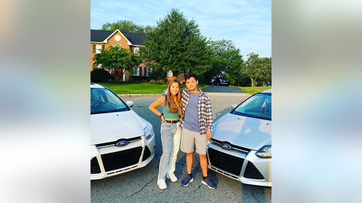 Hannah and Collin Gosselin pose for a picture in between two matching silver Ford cars