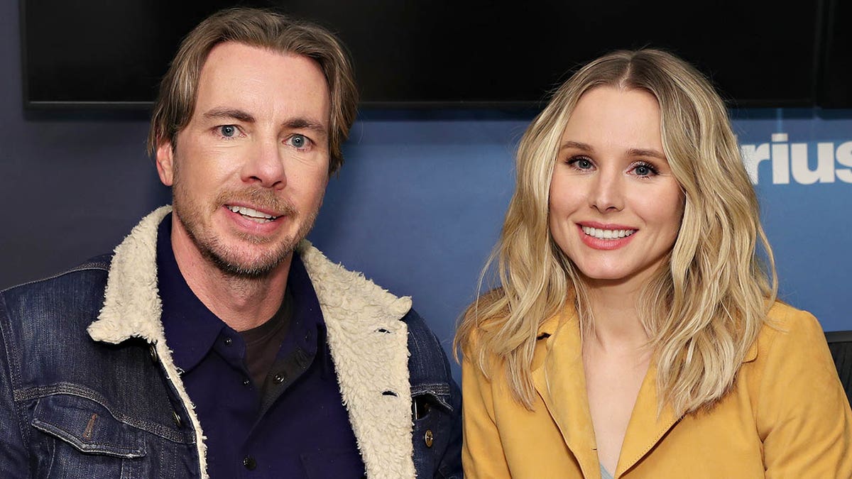 Dax Shepard in a sherpa jean jacket sits next to Kristen Bell in a custard colored jacket