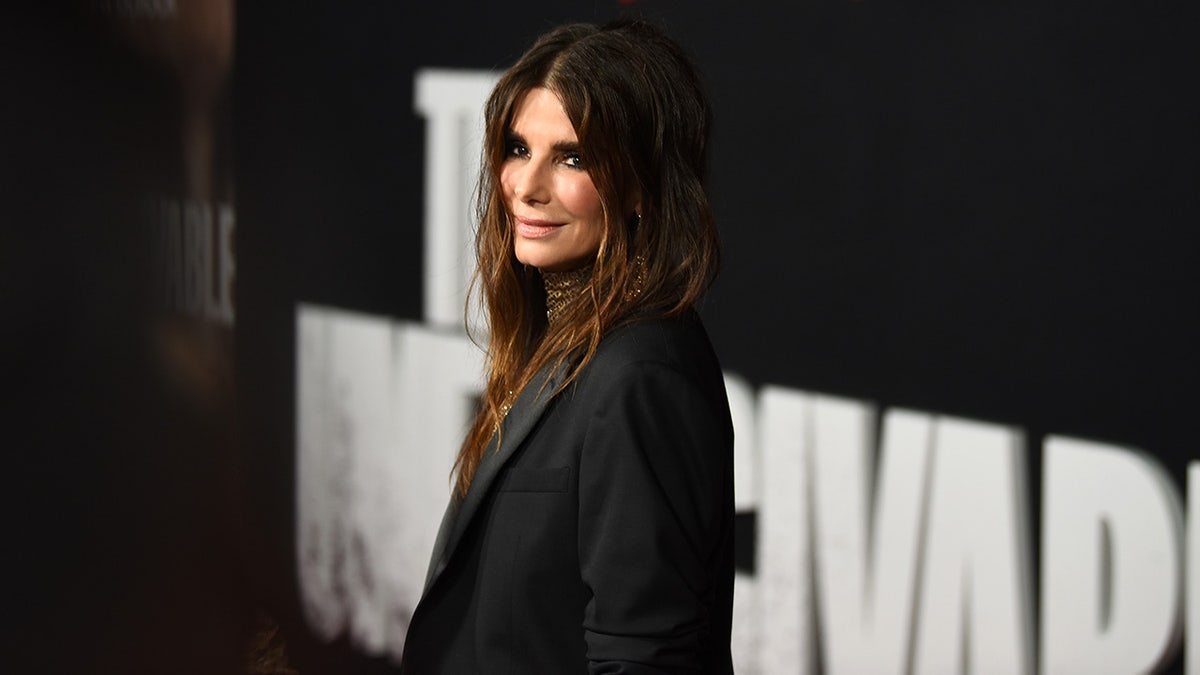 Sandra Bullock looks slightly over her shoulder in a black outfit on the carpet 