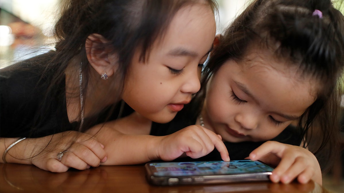 Two sisters playing on a smartphone.