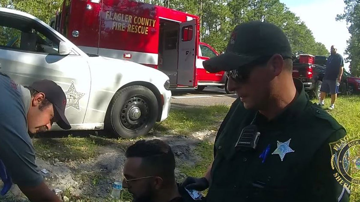 deputy on ground with ambulance behind him