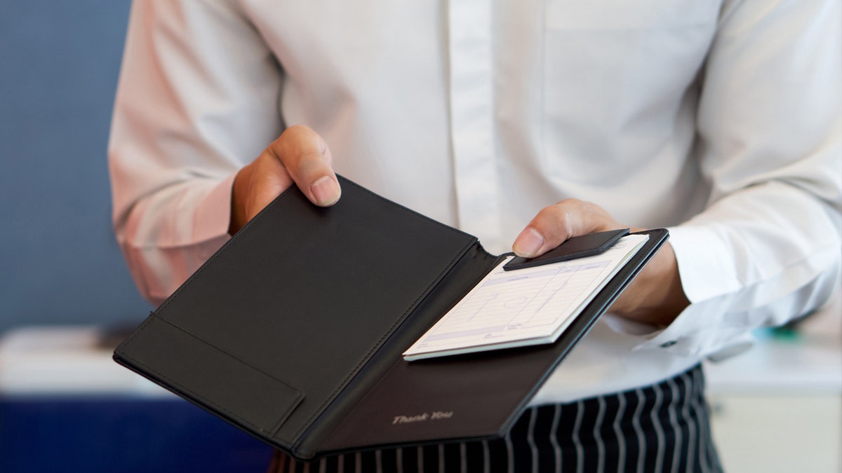 A server presents a receipt held inside a checkbook.