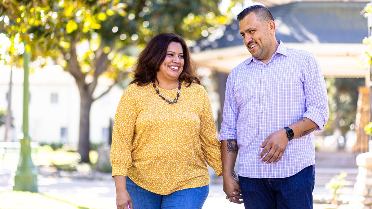 Plus-size woman walks hand-in-hand with her taller male partner.