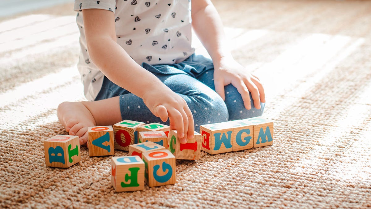 child plays with wooden cubes with colorful letters